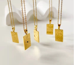 Macro view of 18K gold-plated tarot necklaces with celestial relief motifs on rectangular pendants