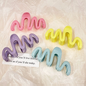 Macaron wave-shaped hair claws in four colors on a white minimalist background
