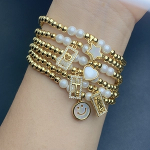 Layered gold bead and pearl bracelet set with heart, cross, and shell smile charms