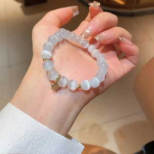 Detailed macro of translucent cat eye beads with a gold star charm on the bracelet