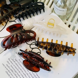 Detail of large butterfly petal hair claws in amber and cream on a vintage magazine