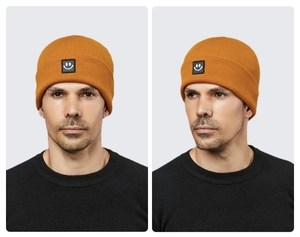 Close-up of ginger yellow knitted beanie featuring a square black smiley face patch detail