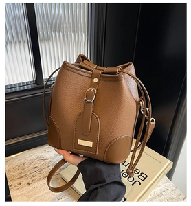 Close-up of brown lychee grain bucket bag with drawstring and golden metal buckle details