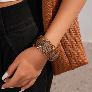Close-up of wide leopard print acrylic resin bangle with glossy finish on model wrist