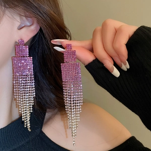 Close-up of dangling tassel earrings with purple gradient crystals on a female model
