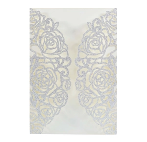 Detail of laser-cut rose pattern on ivory wedding card with silver glitter finish
