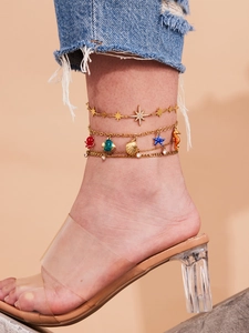 Detail of gold layered anklet featuring colorful enamel marine charms and zircon stars