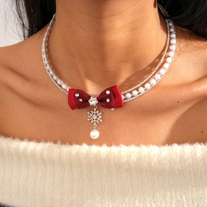 Close-up of red ribbon bow necklace with rhinestone chains and snowflake pendant
