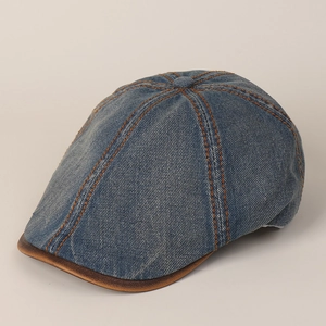 Detailed macro view of navy denim newsboy cap with orange stitching and leather trim