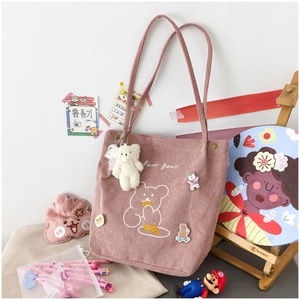 Close-up of pink corduroy tote bag featuring bear embroidery and cute plush pendant