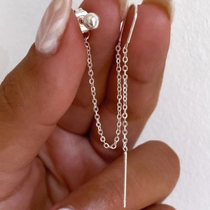 Detail of s925 silver tassel clover earring with dangling metal chain held by hand