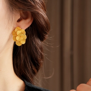 Gros plan de boucles d'oreilles fleuries plaquées or 18 carats portées par un mannequin