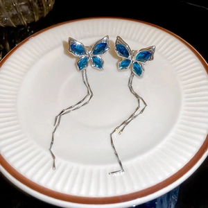Vue détaillée des boucles d'oreilles papillon avec cristaux bleus et longs glands
