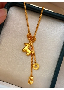 Macro detail of a 24K gold-plated necklace with horse pendant and copper coin charm