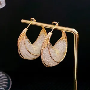 Golden mesh crescent earrings with crystal stone filling on minimalist metal display stand