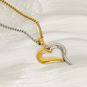 Two-tone heart pendant necklace with gold and silver box chain on white fabric