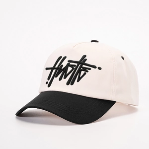 Two-tone beige and black baseball cap with 3D HN embroidery in a street style look