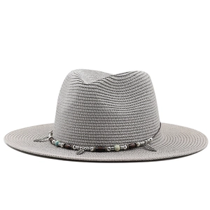 Detail of grey straw fedora hat with bohemian beads and metallic feather pendants