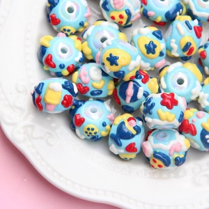 Macro shot of blue hand-painted DIY beads with colorful floral patterns in a white dish