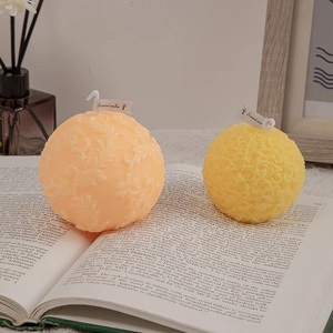 Floral sphere scented candles in orange and yellow set on a book for home decor