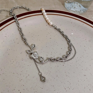 Detail of a cat-eye stone necklace with a metal face mask pendant and pearls