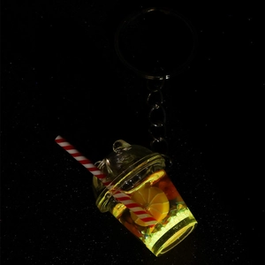 Luminous lemon milk tea cup keychain with glowing effect on a dark background