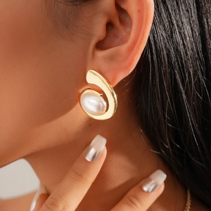 Detail of a gold spiral earring with a white faux pearl on model for a luxury look