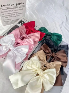 Flat lay of multiple colorful satin bow hair clips in various elegant pastel shades