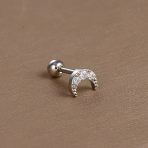 Macro shot of silver crescent moon cartilage earring with cubic zirconia and ball back
