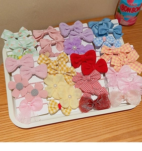 Flat lay of colorful bow hair ties and floral clips on a wooden tray with bright lighting
