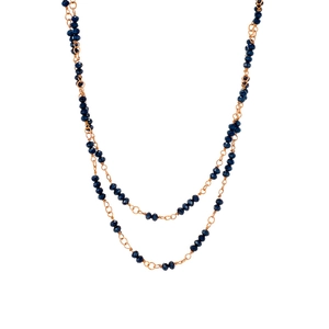 Long gold chain necklace set with dark blue faceted beads and layered styling