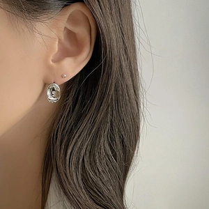 Close-up of minimalist liquid metal silver earrings with irregular textured surface