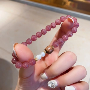 Detailansicht der rosa Erdbeerquarz-Perlen mit einer braunen Holzperle auf dem Armband