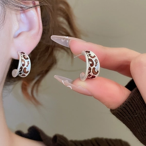 Détail des boucles d'oreilles en C à motif léopard avec base argentée et émail vintage