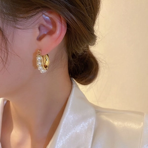 Vintage gold U-shaped hoop earrings with high-luster pearls worn by model closeup