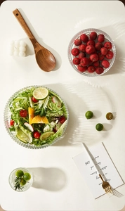 Detailed top view of a vertical stripe glass salad bowl with a wooden spoon and fresh salad