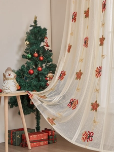 Detail der Weihnachtsgardine aus Spitze mit gestickten Glocken und Festtagsmotiven