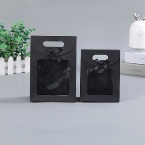 Detail of two black paper gift bags with transparent window and decorative bow ribbons