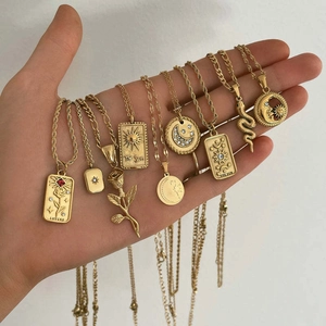 Detailed close-up of 18k gold plated tarot and snake pendants with unique engravings