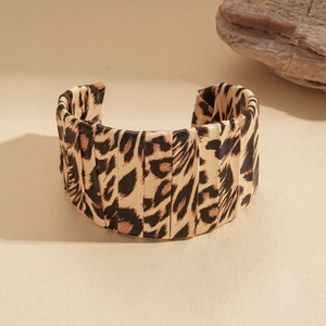 Close-up of leopard print faux leather cuff bracelet on a natural wood background