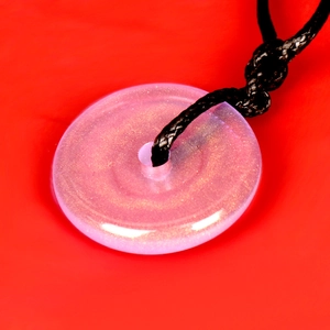 Close-up of translucent pink jade-like pendant with gold glitter and black cord
