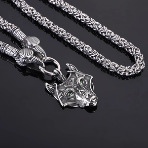 Close-up of Viking wolf head pendant with green eyes and Celtic patterns on woven chain