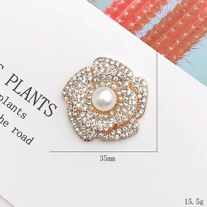 Zinc alloy flower brooch with rhinestones and pearl center on a white background