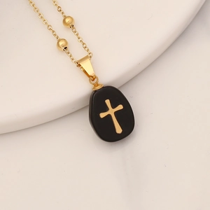 Elegant gold chain necklace with a black stone pebble pendant and gold cross accent