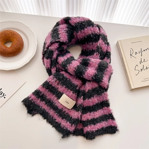 Detail of pink and black striped wool scarf with ins label among lifestyle props