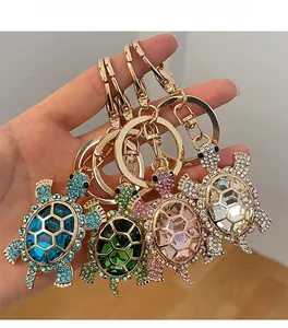 Close-up of four colorful turtle keychains with crystal rhinestones held in hand