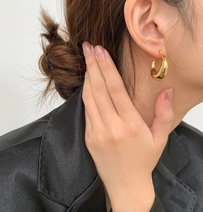 Primer plano de pendientes de media luna en oro de 18K sobre perfil de modelo