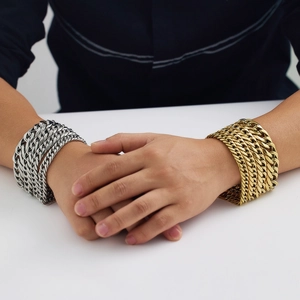 Dettaglio di bracciali a catena cubana spessa in oro e argento su polso di modello