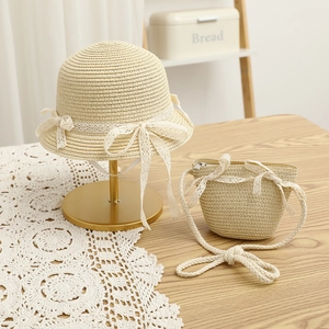 Close-up of summer girls straw hat and matching crossbody bag with white lace bows