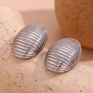 Macro shot of silver ribbed oval earrings on stone texture showing metallic details